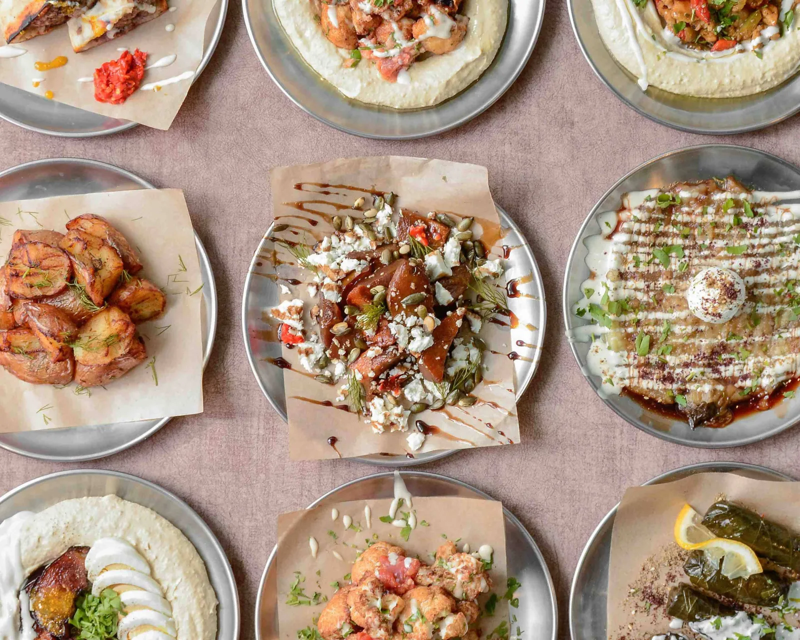 Mesa llena de platos de DosManos: pitas, hummus y entrantes